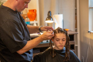 Pete The Lice Guy performing a head lice treatment on a young girl in head lice salon